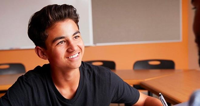 一名年轻的高中男生坐在教室里微笑着.