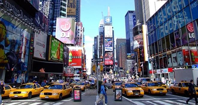纽约人在时代广场一排排黄色出租车前过马路的街景.