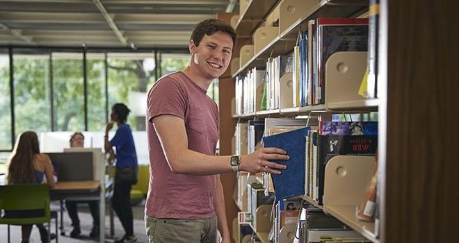 man pulling book off of library shelf